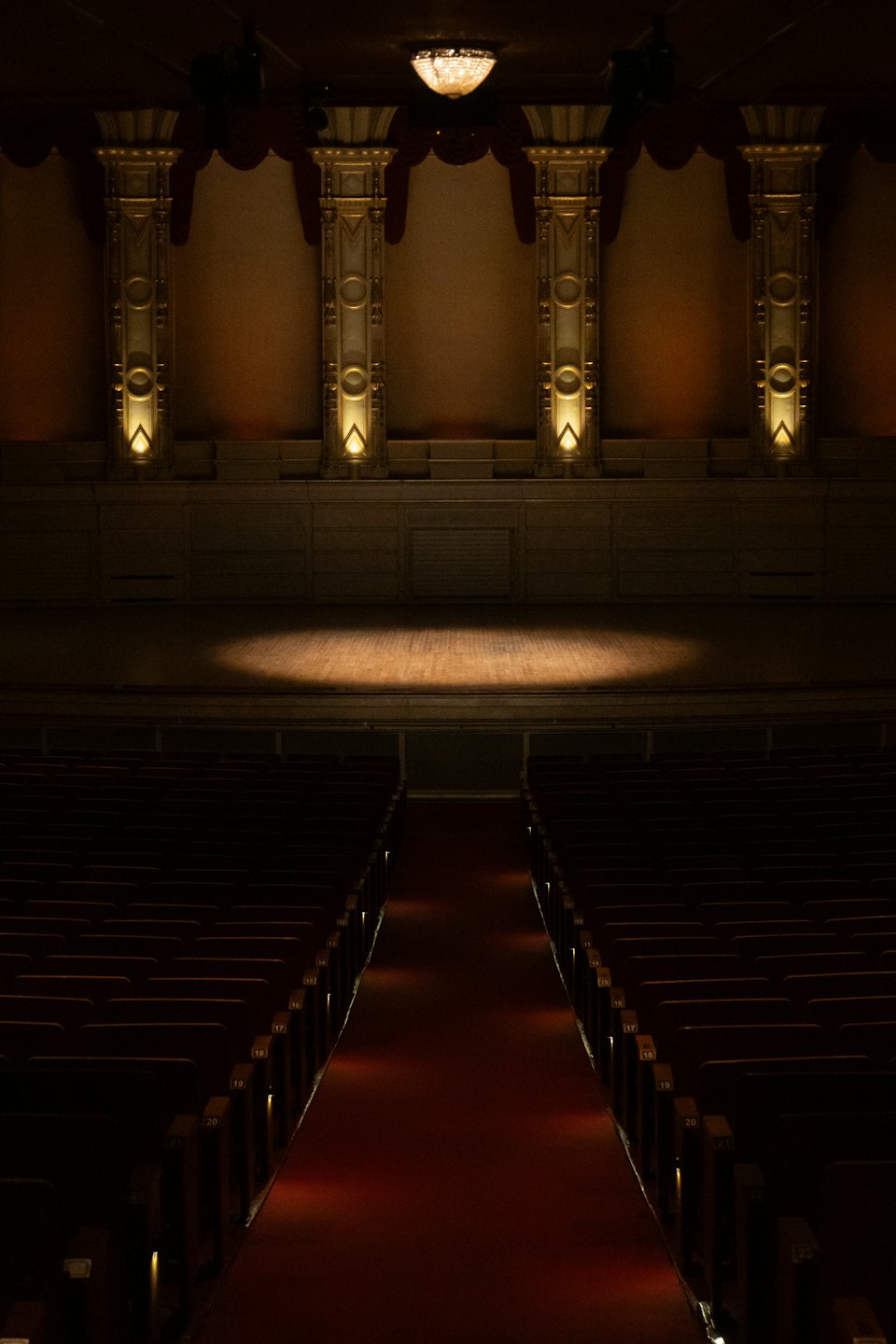 Un riflettore illumina un palco vuoto in un grande ed elegante auditorium.