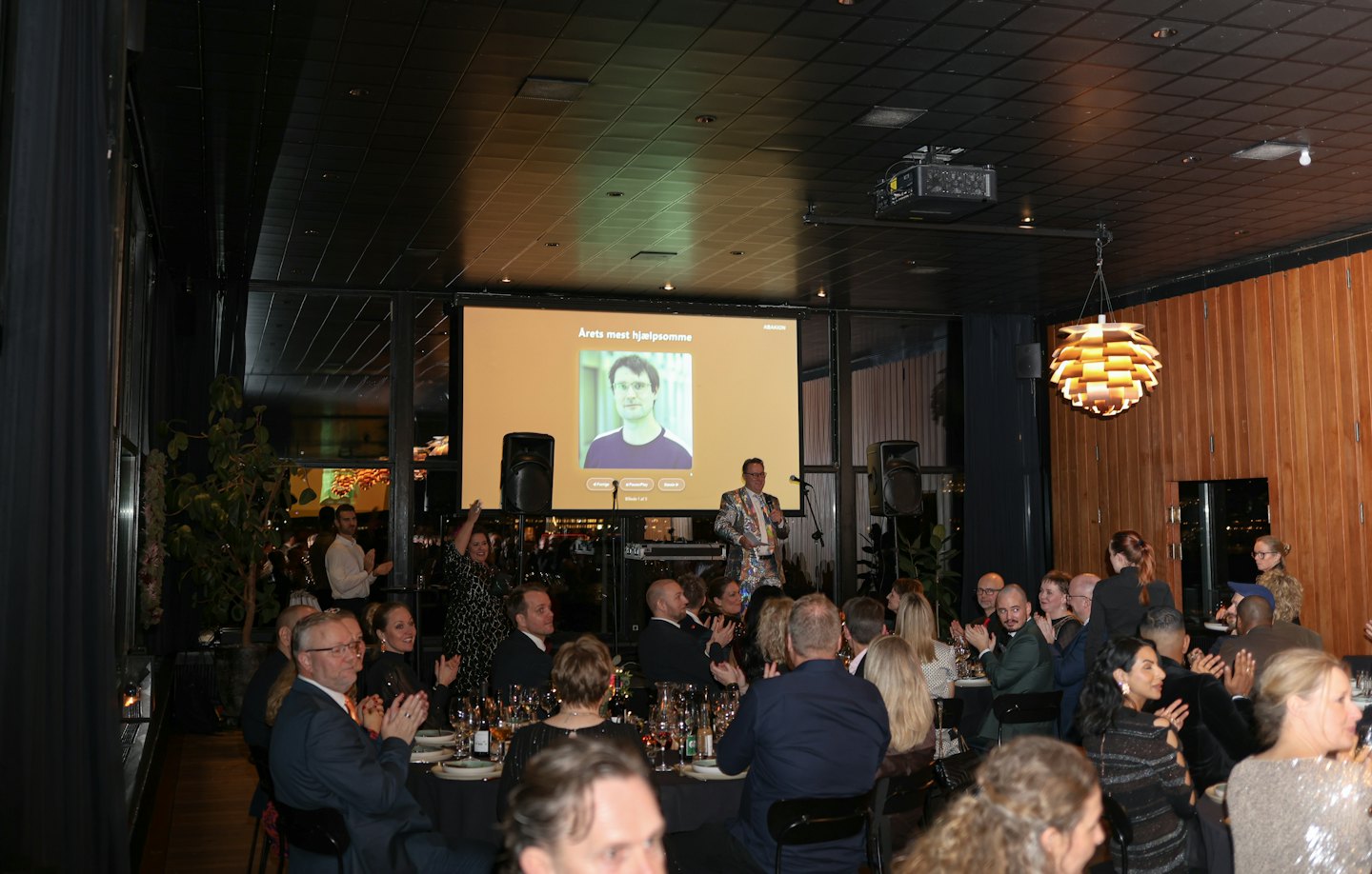 Un relatore sul palco si rivolge a un pubblico durante un gala formale.
