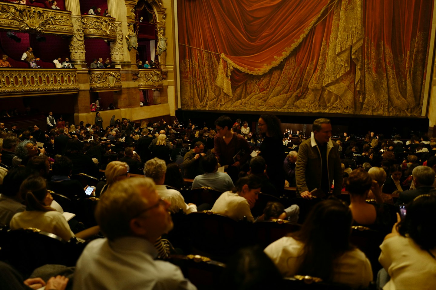 Il pubblico attende uno spettacolo in un grande teatro.